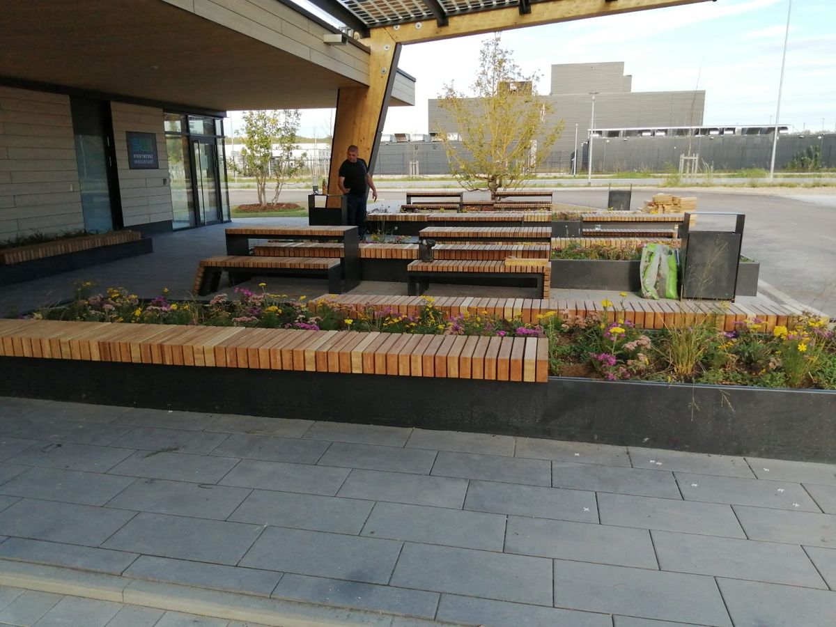 Überdachter Sitzbereich mit Holzbänken auf einem Firmengelände